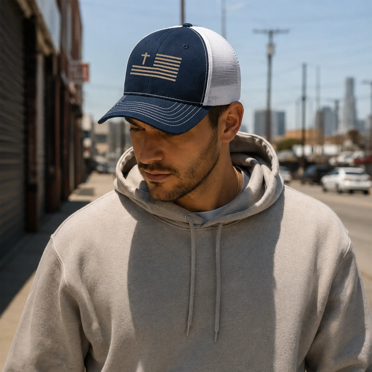 Urban lifestyle photo of Canvas & Iron Faith Trucker Cap in navy and white with sand embroidery