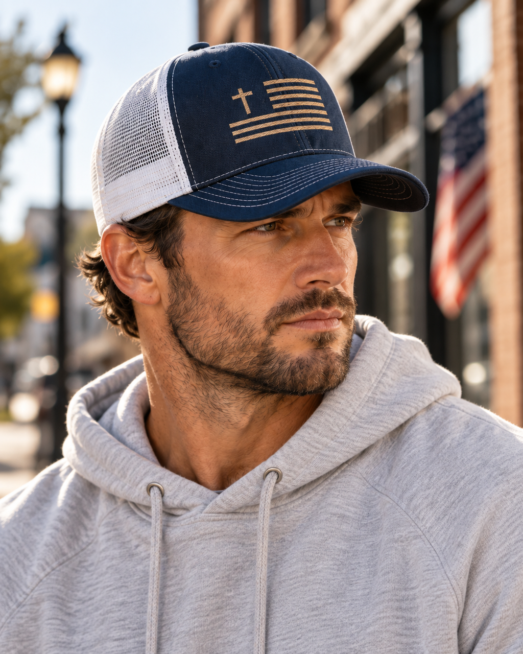 Lifestyle view of navy and white Canvas & Iron Faith Trucker Cap with sand embroidered cross flag
