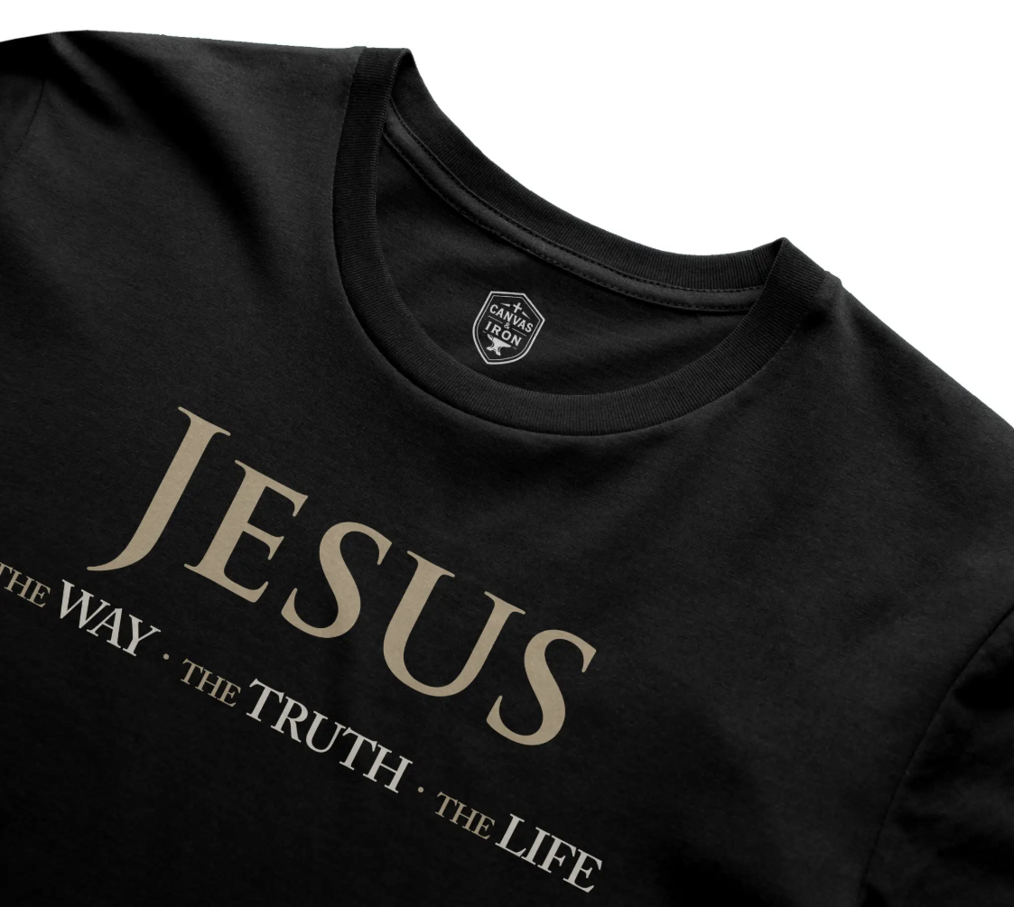 Angled detail of Canvas & Iron Jesus graphic and shield neck print on black Supima tee